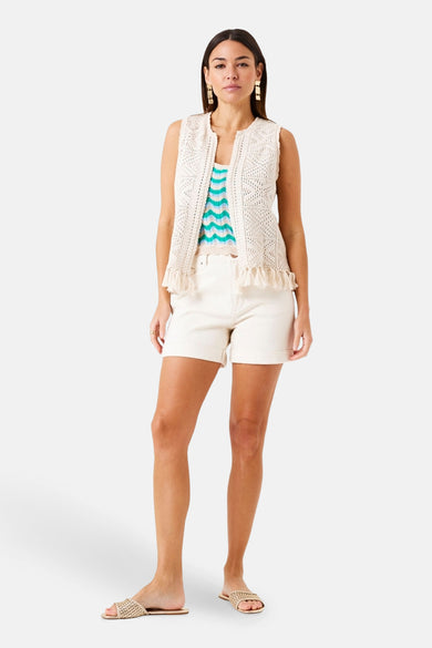 Gilet beige de GARCIA avec une texture crochetée et des franges décoratives, porté avec un short blanc et un haut rayé.