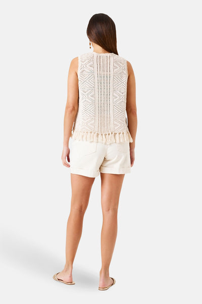 Gilet beige en crochet de GARCIA, avec détails ajourés et franges décoratives au bas, porté avec un short blanc.
