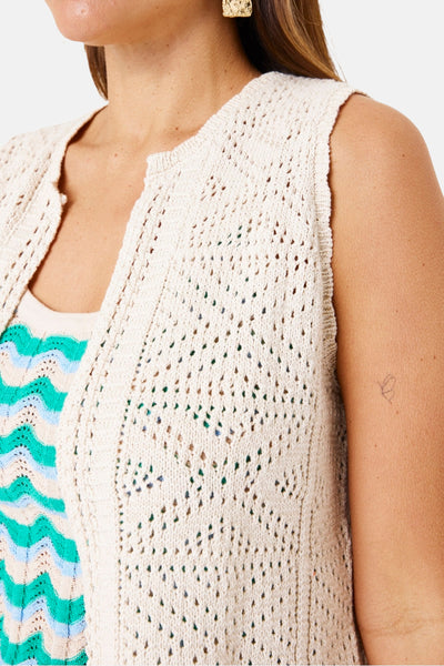 Beige gehaakt vest van GARCIA, gedragen over een top met turquoise en beige golvende strepen, met een gouden oorbel.