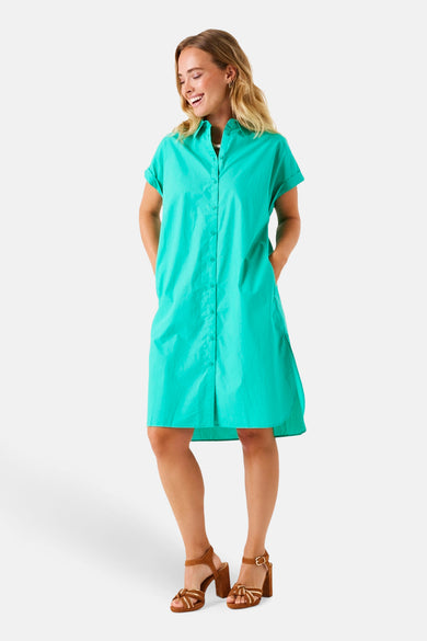 Robe à manches courtes verte de GARCIA, coupe chemise boutonnée et portées avec des talons hauts marron.