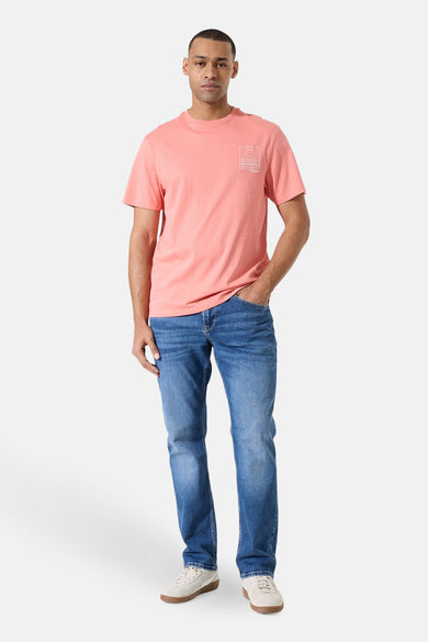 T-shirt rose à manches courtes de GARCIA, avec un motif imprimé discret sur la poitrine, porté avec un jean bleu et des baskets crème.
