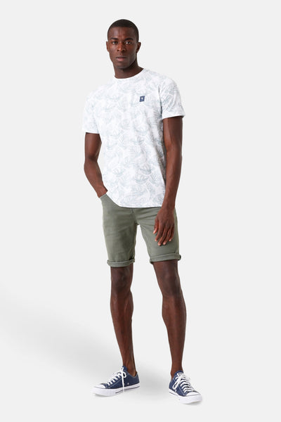 T-shirt à manches courtes blanc de GARCIA, avec un imprimé de feuilles et porté avec un short kaki et des baskets bleues.
