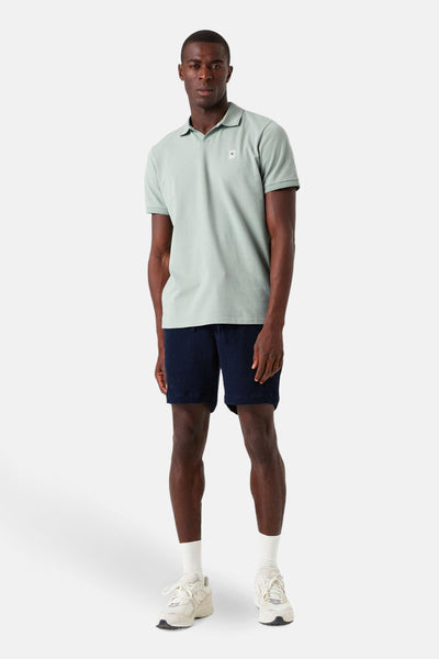 Polo kaki à manches courtes de GARCIA, porté avec un short bleu marine texturé et des baskets blanches.