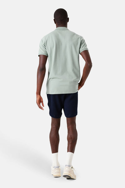 Polo à manches courtes kaki de GARCIA, vu de dos, porté avec un short bleu marine à texture gaufrée.