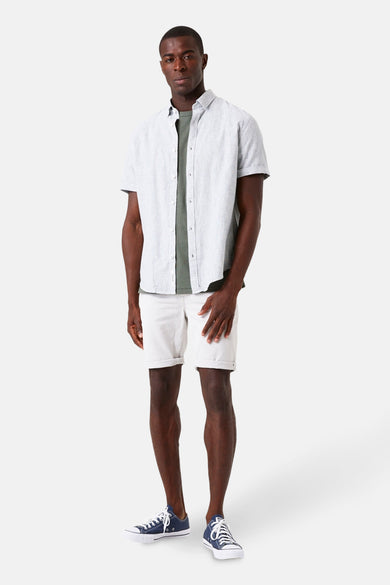 Chemise à manches courtes verte par GARCIA, portée ouverte sur un t-shirt et un short blancs.