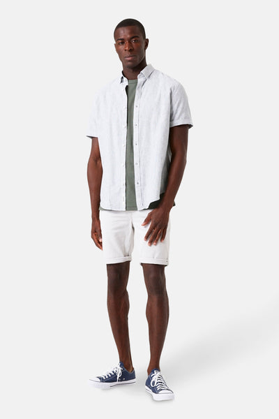 Chemise à manches courtes verte par GARCIA, portée ouverte sur un t-shirt et un short blancs.