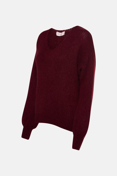 Pull col V rouge bordeaux par AMELIE ET AMELIE, en maille duveteuse et manches longues bouffantes.
