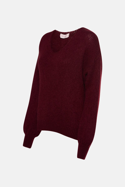 Pull col V rouge bordeaux par AMELIE ET AMELIE, en maille duveteuse et manches longues bouffantes.
