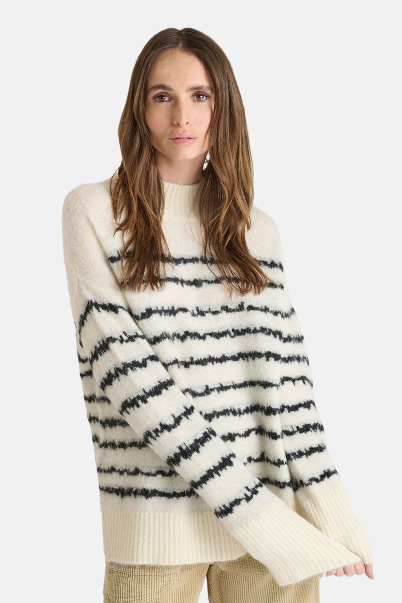 Pull beige à rayures noires de Le Temps des Cerises, en maille douce, porté avec un pantalon beige en velours côtelé.