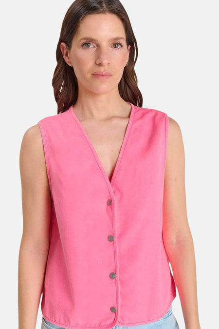 Gilet rose de Le Temps des Cerises, sans manches, avec un col en V et des boutons frontaux, porté sur un jean.
