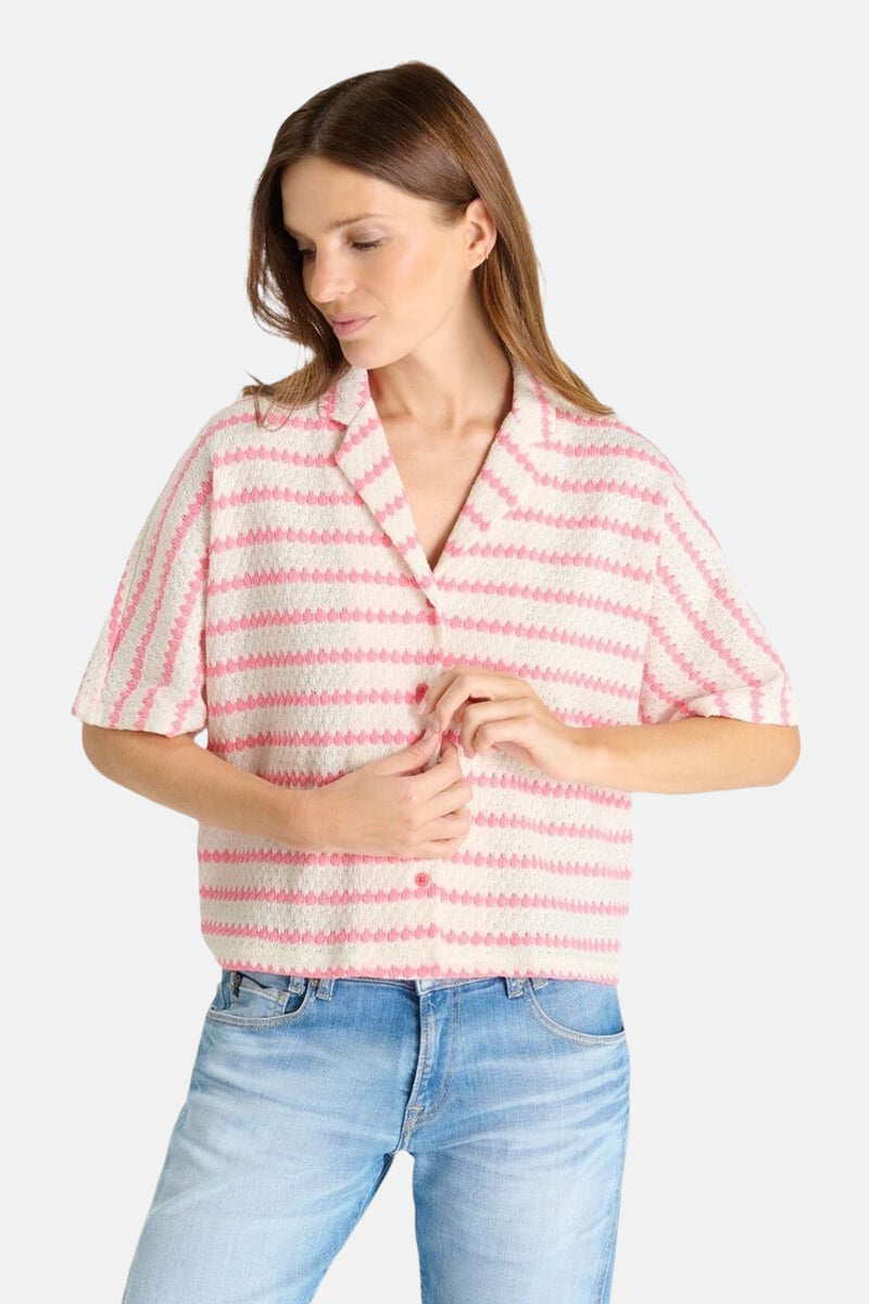 Multikleurig poloshirt van Le Temps des Cerises, met roze en witte strepen, gedragen met een lichtblauwe jeans.