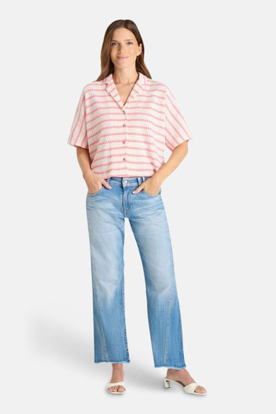 Multikleurig poloshirt van Le Temps des Cerises, met roze en witte strepen, gedragen met een spijkerbroek en muiltjes.