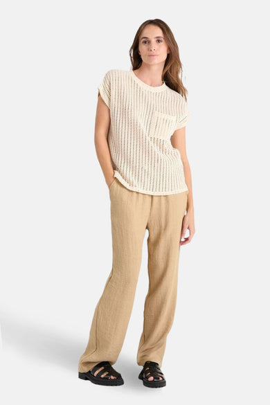 T-shirt ajouré beige de Le Temps des Cerises, porté avec un pantalon beige ample et des sandales noires.
