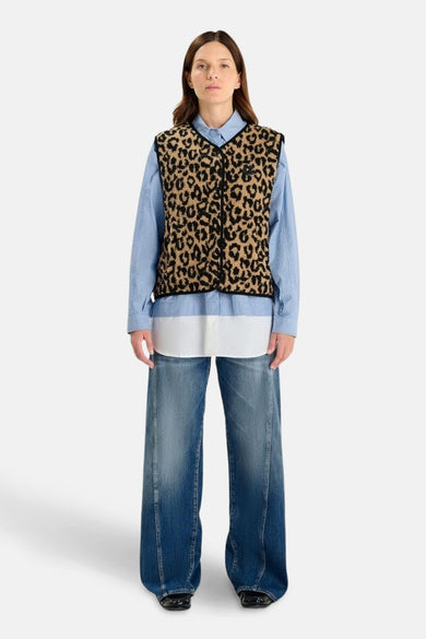 Veste sans manches multicolore de Le Temps des Cerises, à motif léopard, portée avec une chemise bleu clair et un jean ample.