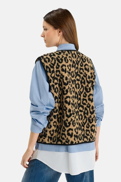 Multikleurig mouwloos vest van Le Temps des Cerises, met luipaardprint, gedragen over een gestreept overhemd.