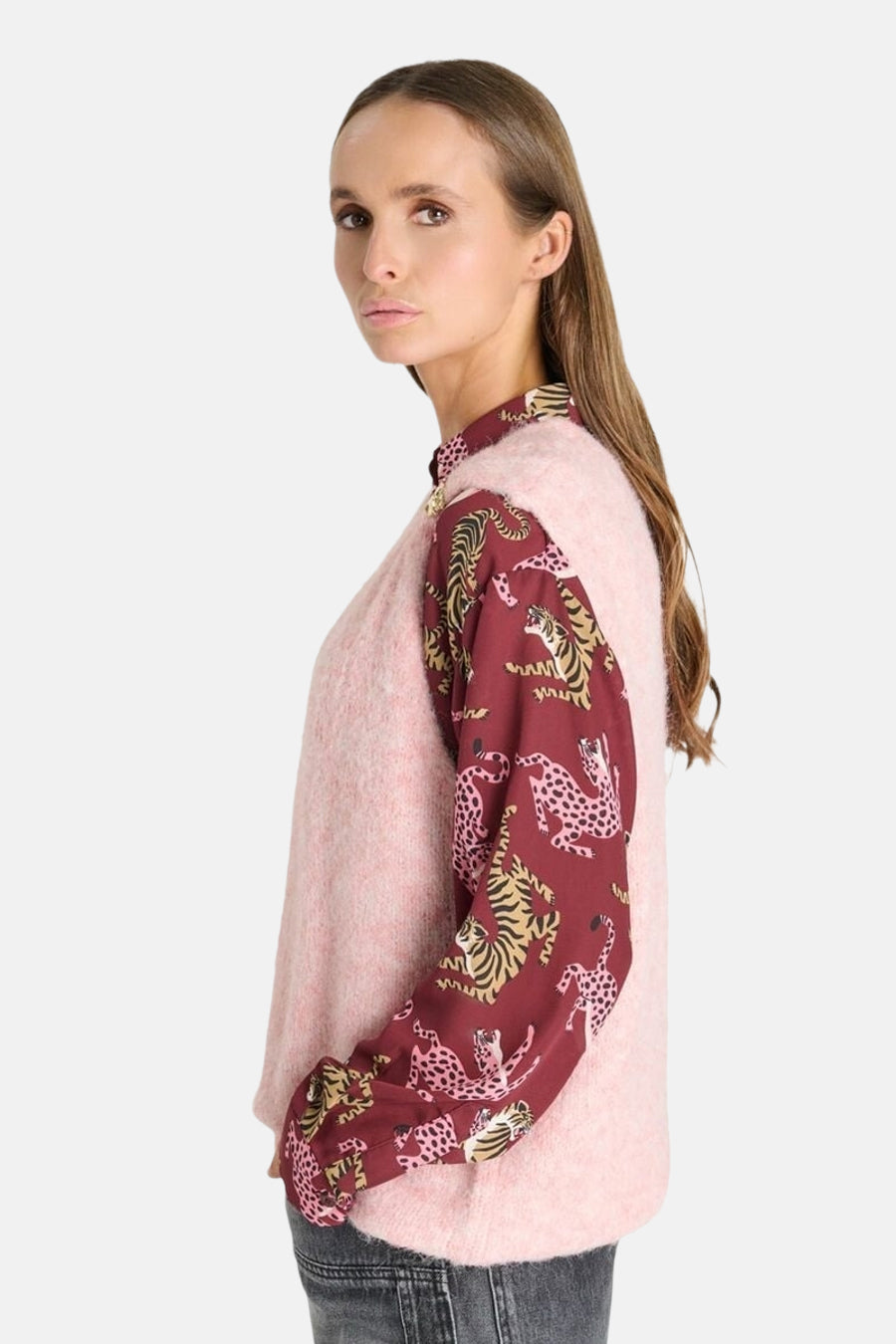 Pink sleeveless gilet with soft fuzzy texture, worn over burgundy animal-print blouse, side view on model