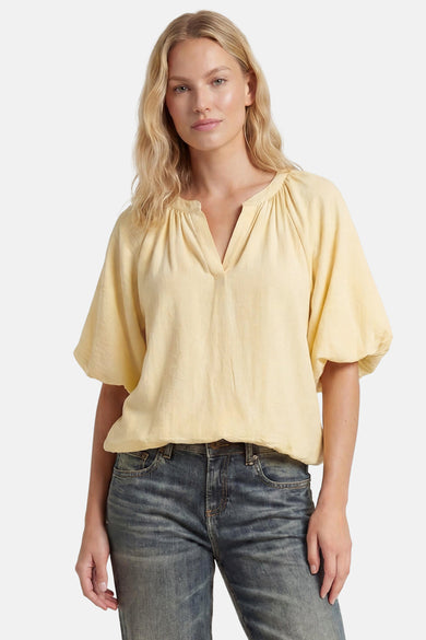Yellow 3/4 sleeve blouse with gathered neckline and flowy sleeves, worn with dark jeans, front view