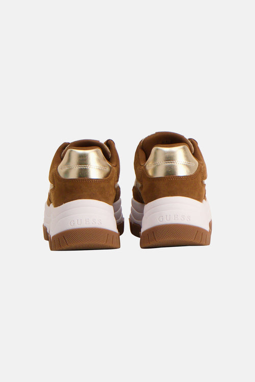 Bruine Guess-sneakers met gouden bies op de hiel en dikke witte zool.