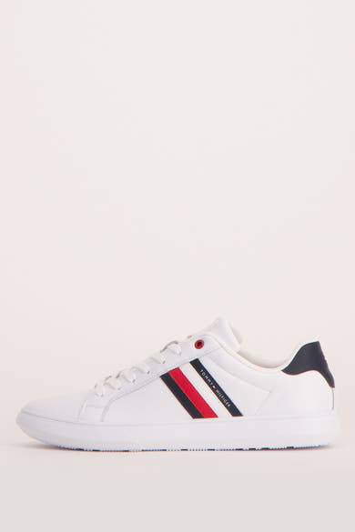 Baskets blanches par Tommy Jeans avec rayure bleu marine et rouge sur le côté, vue de côté.
