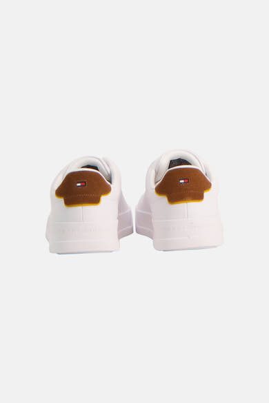 Sneakers blanches de TOMMY JEANS, vues de l'arrière, avec empiècements de talon marron en suède, liseré jaune, logo Tommy Hilfiger et nom embossé.