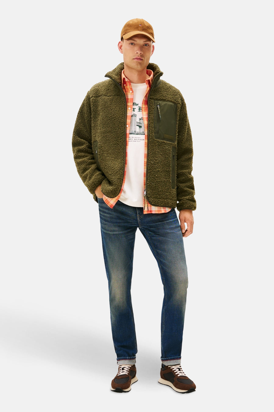 Bruine sneakers van TOMMY JEANS, met witte veters en beige zool, gedragen met een spijkerbroek en een fleecetrui.