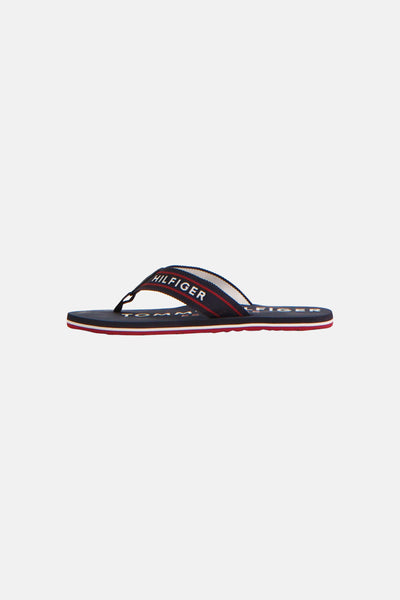 Nu-pieds tongs bleues de TOMMY JEANS, avec inscription du logo sur la bride et semelle à rayures.