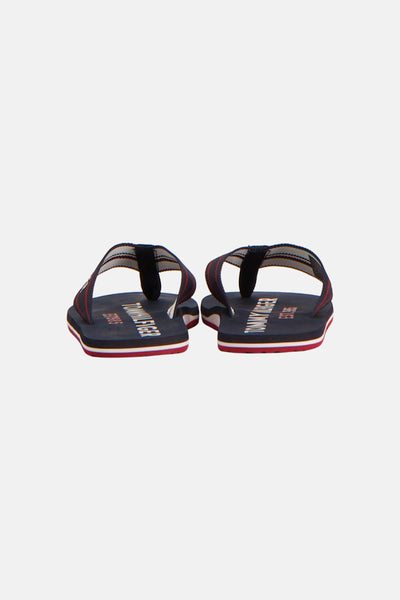 Nu-pieds tongs bleues de TOMMY JEANS, avec des rayures rouges et blanches sur la semelle.