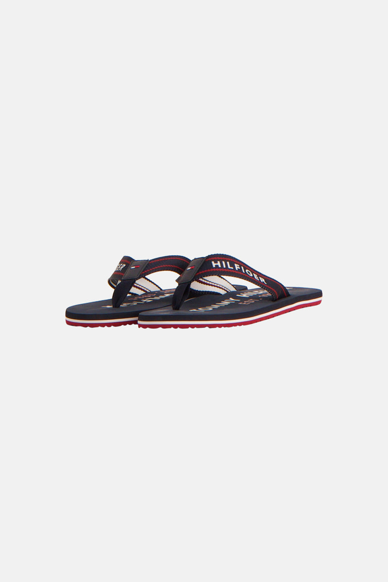 Blauwe teenslippers van TOMMY JEANS, met rode en witte strepen op de zool.