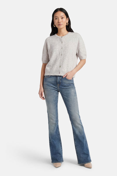 Cardigan gris chiné de Le Temps des Cerises, à manches courtes et coupe ajustée, porté avec un jean bleu et des escarpins nude.
