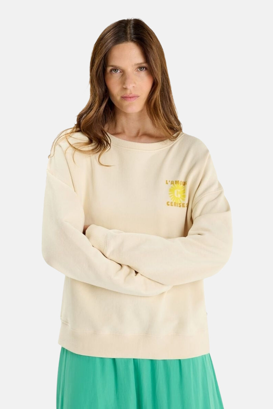 Sweat écru de Le Temps des Cerises, avec un motif fleuri jaune, porté avec une jupe verte.