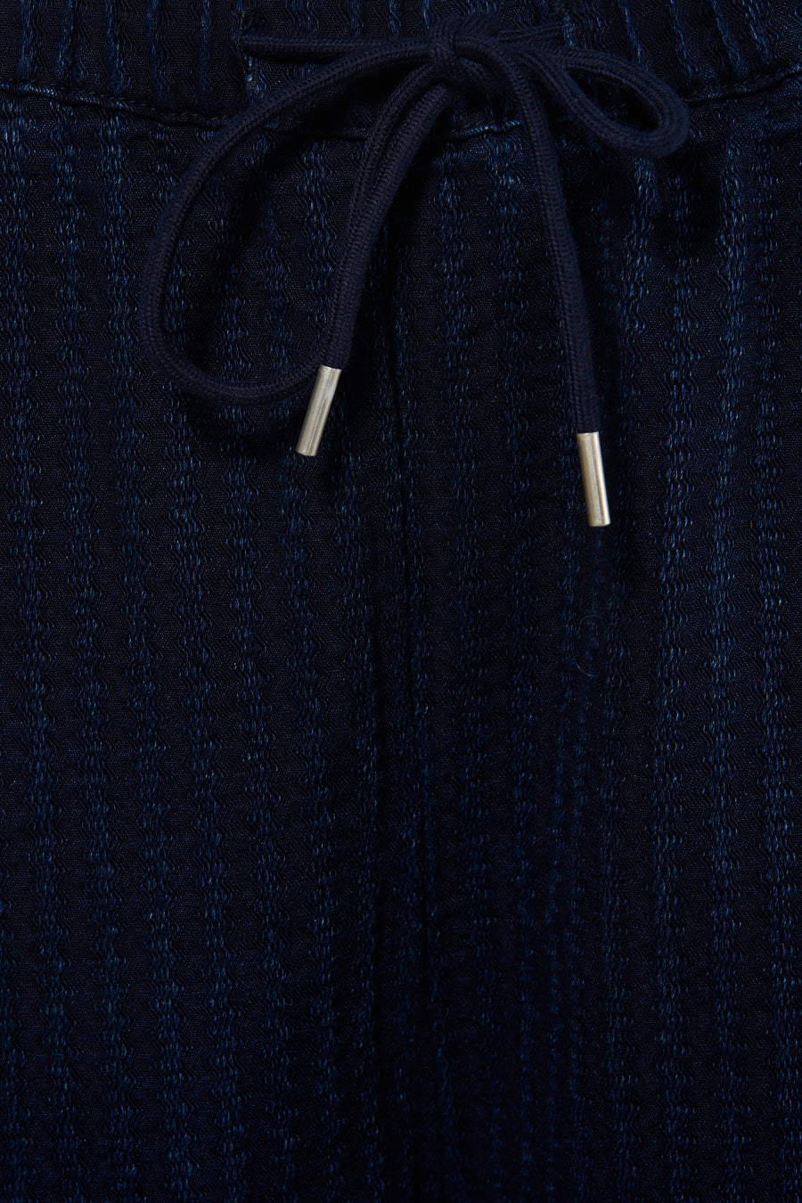 Pantalon en denim bleu foncé d'ADORE, avec une ceinture à cordon de serrage et un subtil motif texturé.