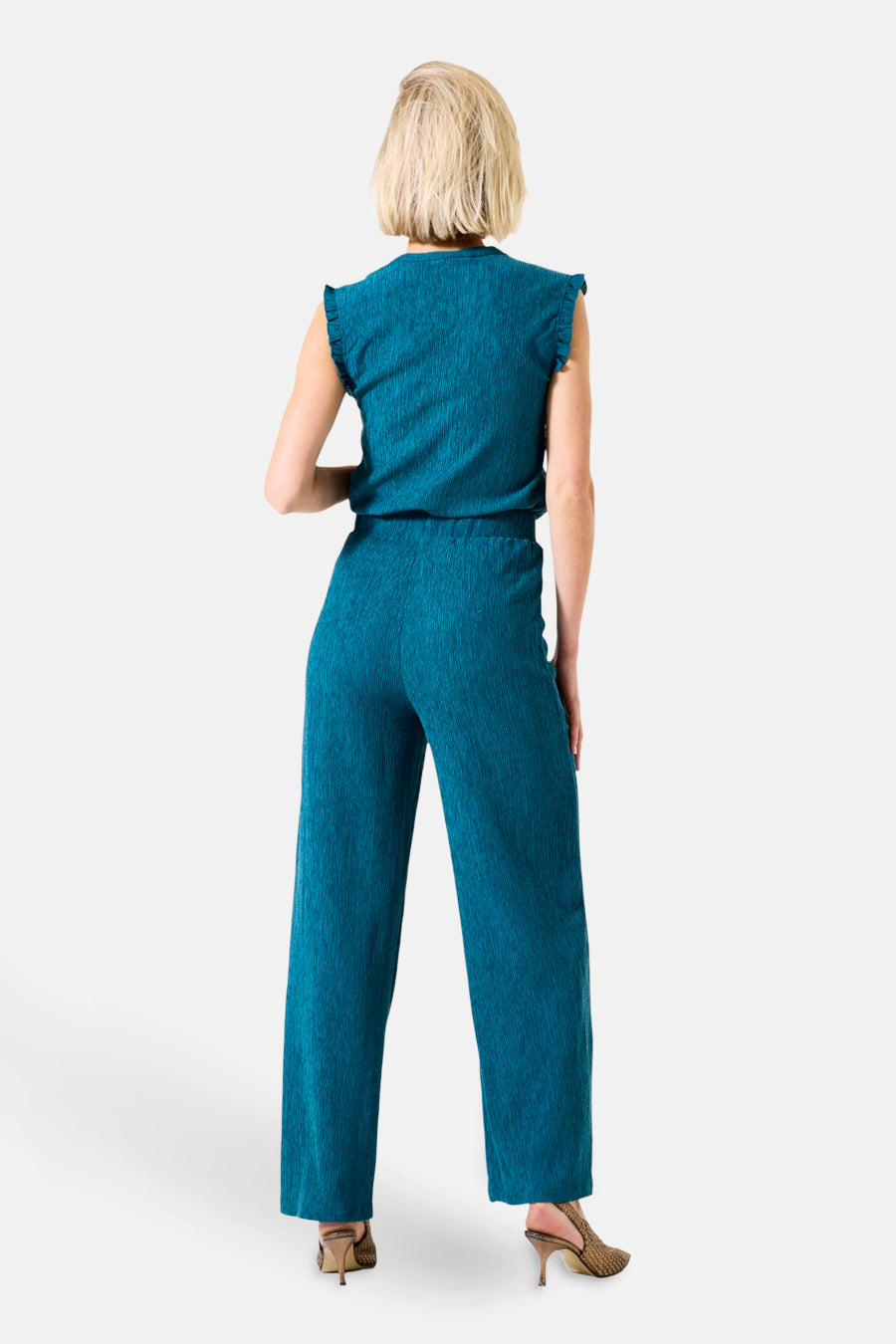 Turquoise broek van GARCIA, wijde pasvorm en geplooide textuur, gedragen met naaldhakken.