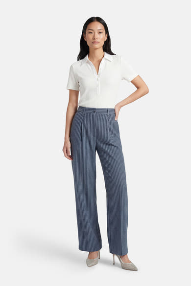 Pantalon de costume bleu par ADORE, à rayures verticales, porté avec un polo blanc et des escarpins scintillants.
