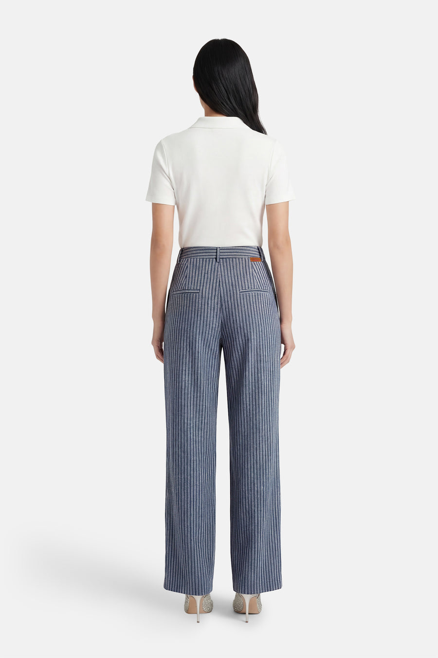 Pantalon de costume bleu rayé de ADORE, coupe droite, avec poches arrière et porté avec un polo blanc.
