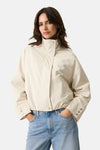 Veste courte écru de GARCIA avec col montant et détails de boutons aux poignets, portée avec un jean bleu.
