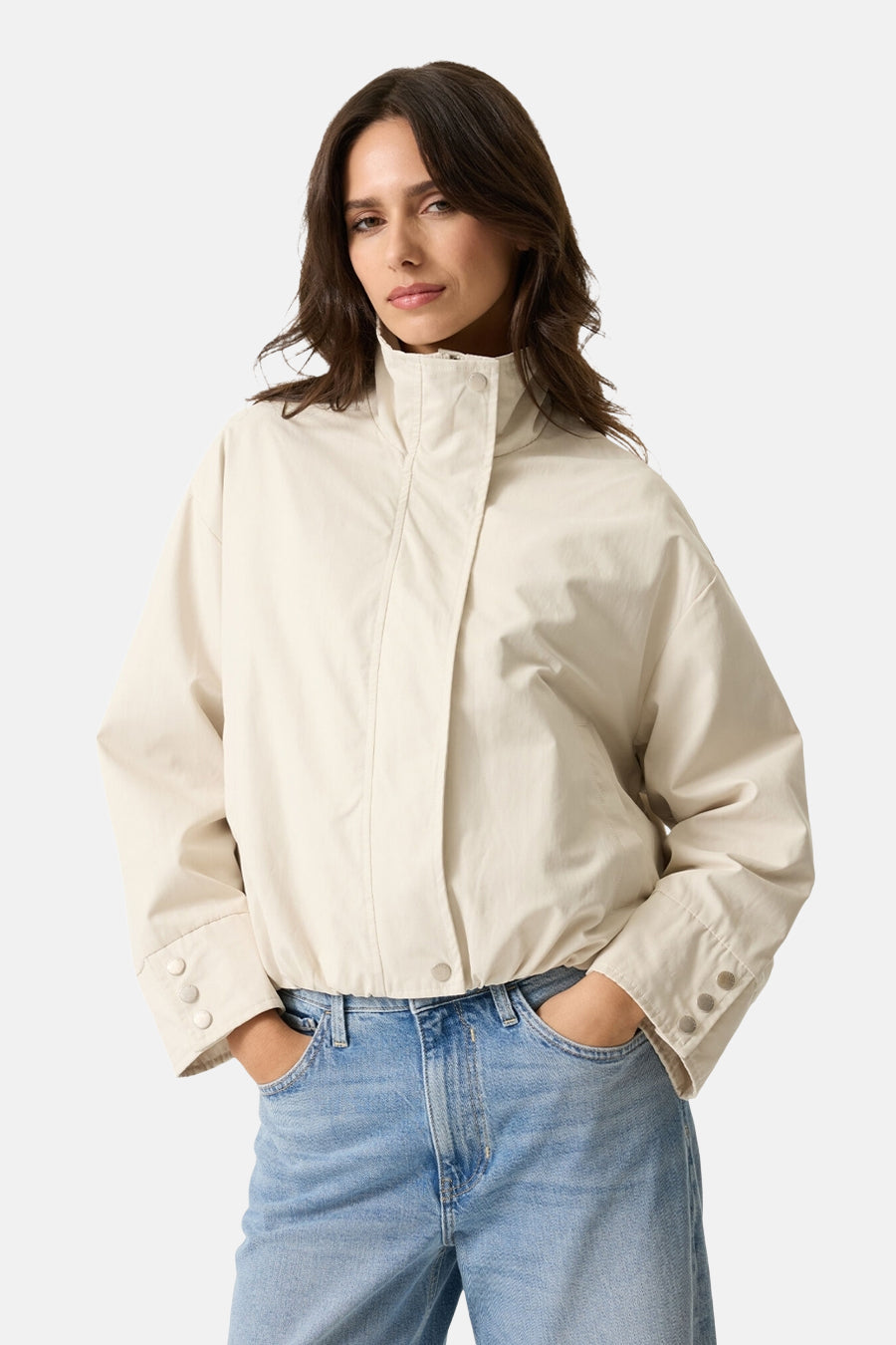 Veste courte écru de GARCIA avec col montant et détails de boutons aux poignets, portée avec un jean bleu.
