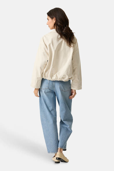 Veste courte écru de GARCIA, avec manches longues et taille élastiquée, portée avec un jean bleu ample.