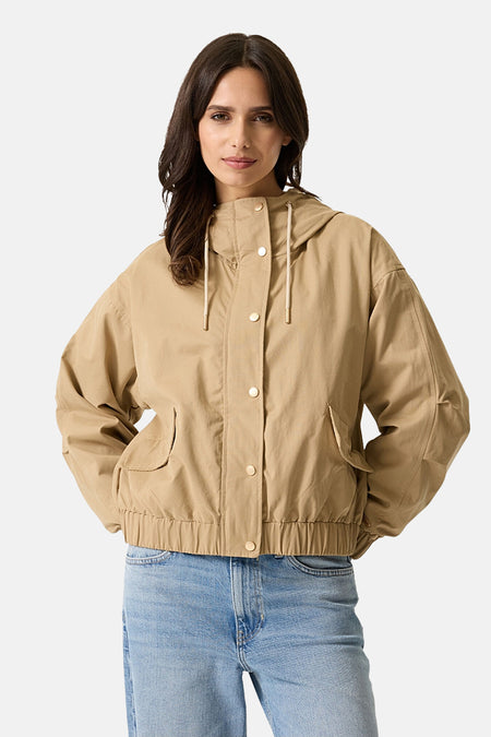 Veste courte beige par GARCIA, avec capuche et boutons dorés, portée sur un jean bleu clair.
