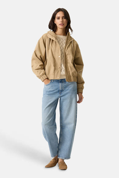 Veste courte beige de GARCIA, avec capuche et manches longues, portée avec un pull et un jean décontractés.

