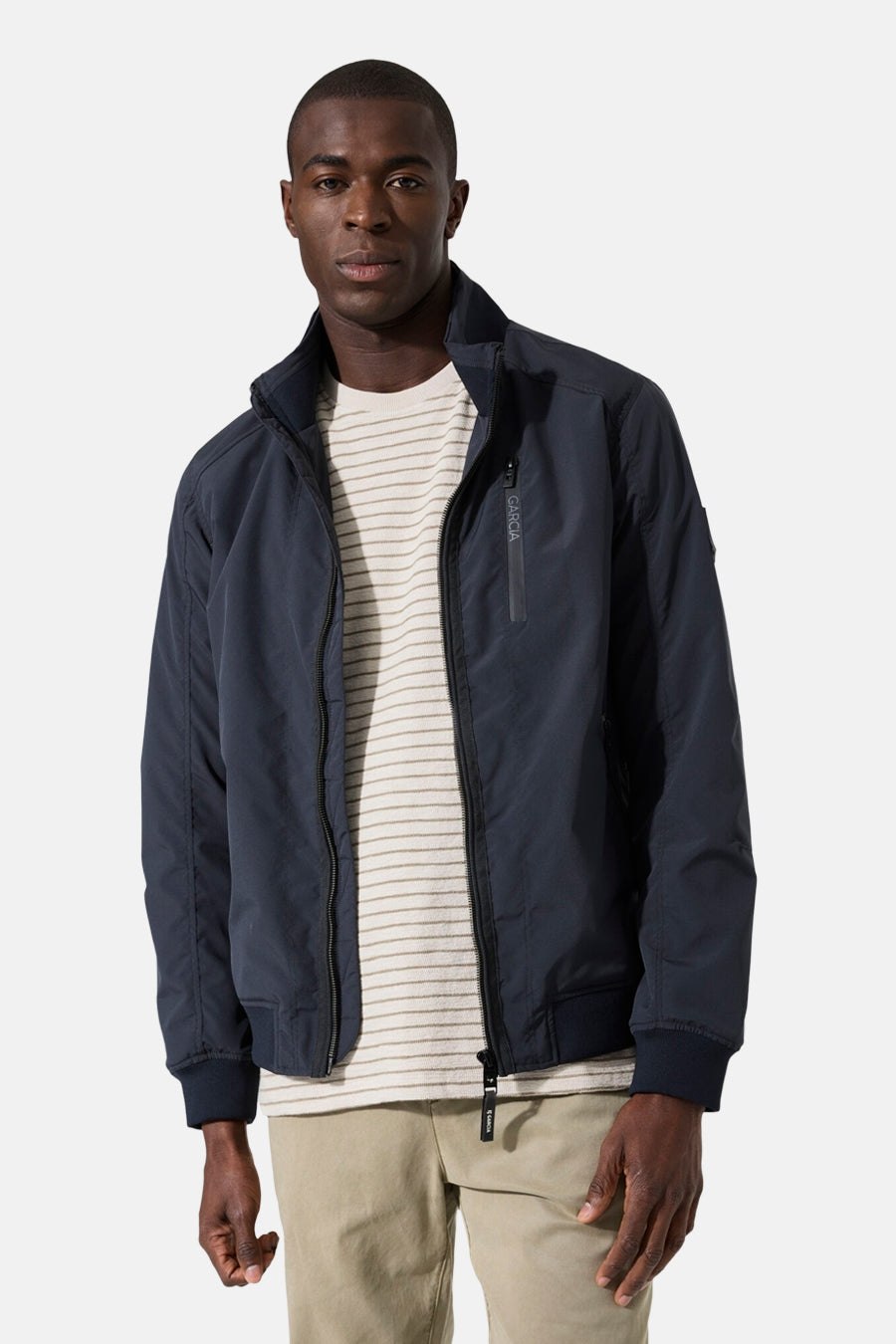 Veste courte bleue de GARCIA, avec une fermeture éclair sur le devant et un t-shirt à rayures neutres en dessous.