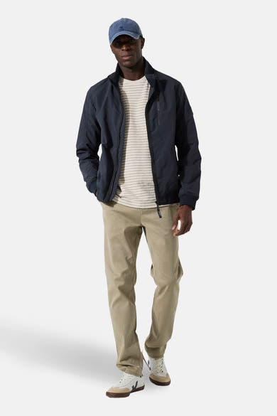 Veste courte bleue de GARCIA, portée avec un t-shirt rayé et un pantalon chino beige.