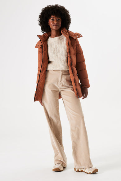 Veste longue cognac de GARCIA, avec col, portée avec un pull et un pantalon en velours côtelé et des baskets.