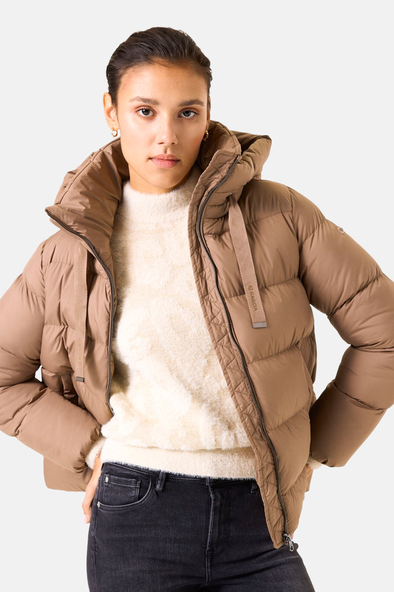 Korte beige jas van GARCIA, met capuchon en ritssluiting, gedragen met een crèmekleurige trui en een zwarte jeans.