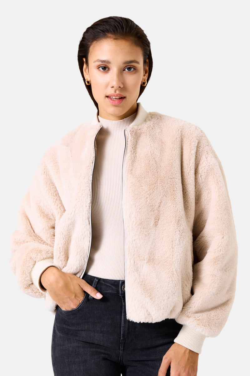 Veste courte beige de GARCIA en fausse fourrure, portée sur un pull en maille fine, avec un jean noir.