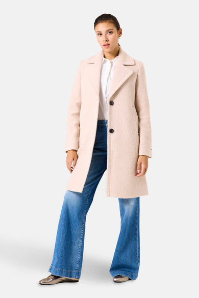 Lange beige jas van GARCIA, met een bouclé textuur en een rechte pasvorm, gedragen met een witte blouse en een wijde jeans.
