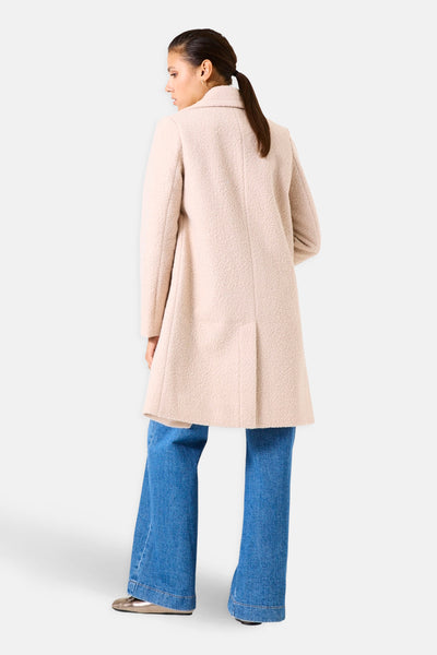 Lange beige getextureerde jas van GARCIA, met een split aan de achterkant, gedragen over een uitlopende jeans.