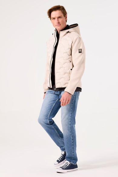 Beige regenjas van GARCIA, met doorgestikt patroon, gedragen met een blauwe jeans en marineblauwe sneakers.
