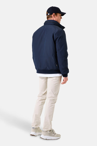 Veste de pluie bleue de GARCIA, vue de dos, portée avec un pantalon beige et des baskets.