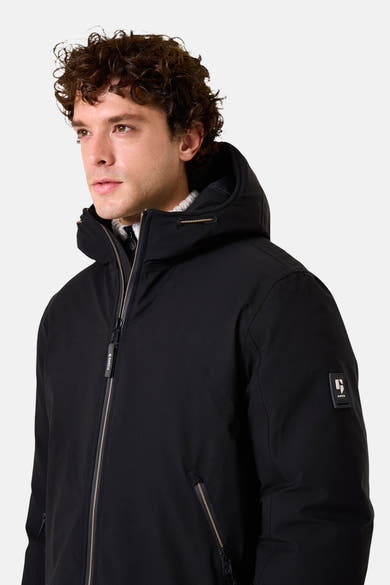 Imperméable noir de GARCIA avec capuche et fermeture éclair, porté sur un pull à col roulé.