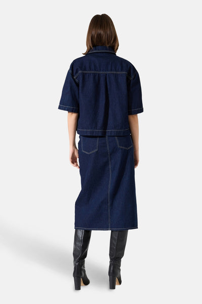 Korte mouwen spijkerblouse in donkerblauw van GARCIA, van achteren gezien, gedragen met een kokerrok en zwarte laarzen.